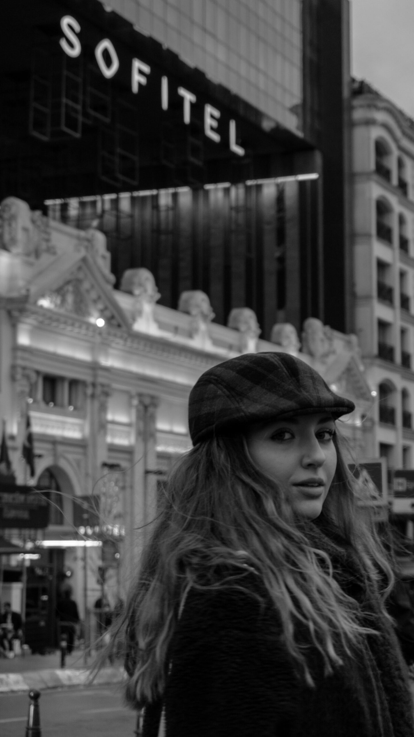 Monochrome image of a woman in an urban setting with modern architecture.