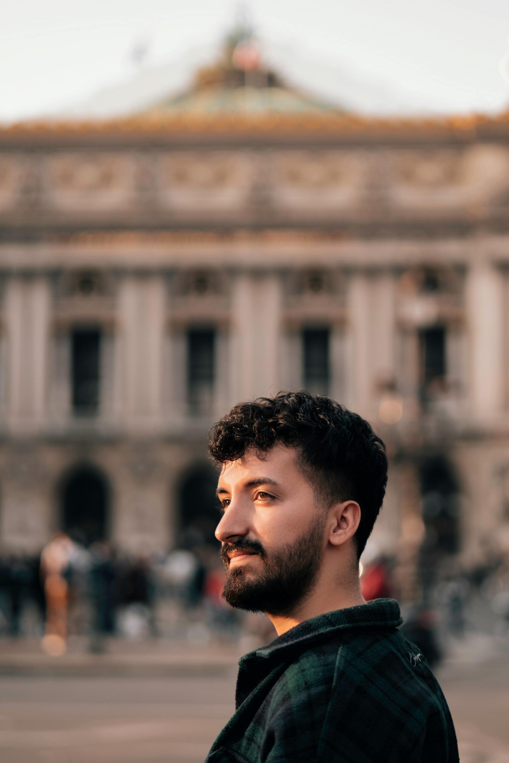 A man stands in front of the historic Palais Garnier in Paris, captured during daylight.