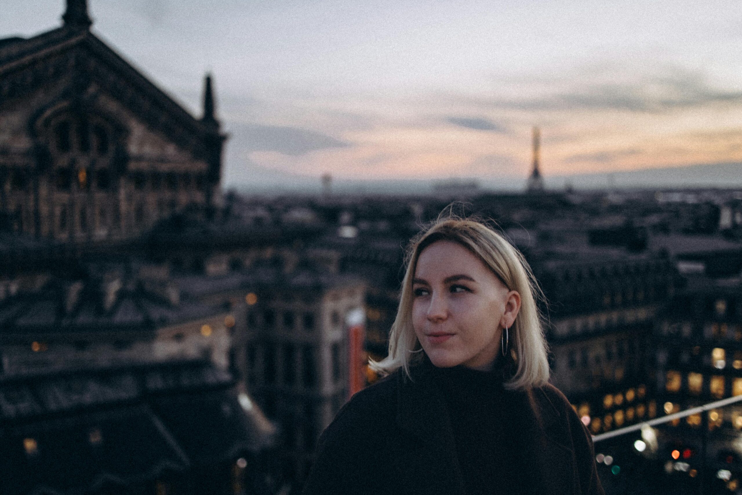 Young woman with Eiffel Tower backdrop during Paris twilight. Dreamy and urban vibe.